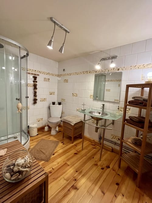 Salle de bain spacieuse au Domaine De La Ferme De Ribeaufontaine avec carrelage blanc, douche vitrée, parquet et double vasque