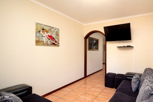 Sala de estar da villa Paradise House em Calheta com área de estar, TV de tela plana, piso em terracota e arte decorativa nas paredes.