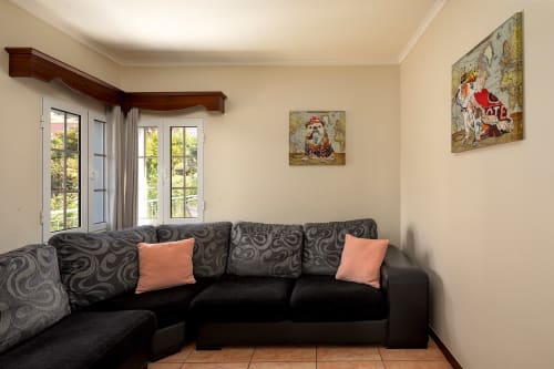 Aconchegante sala de estar com sofá estampado escuro e almofadas coral na villa Paradise House em Calheta