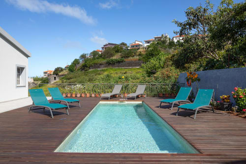 Deck de piscina de villa de luxo em Calheta com espreguiçadeiras turquesas, piscina aquecida e vistas do jardim na encosta