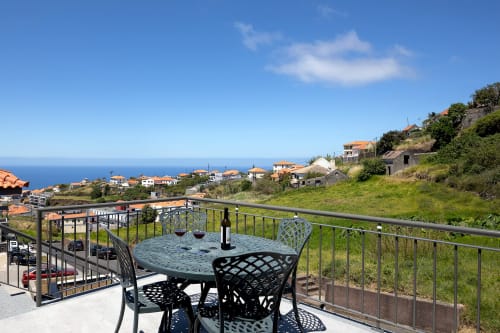 Terraço com vista para o oceano na villa Paradise House em Calheta com mesa de jantar com vista para a aldeia costeira portuguesa