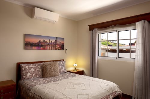 Quarto aconchegante na villa Paradise House Calheta com cama queen, obra de arte com skyline, ar condicionado e vista da varanda