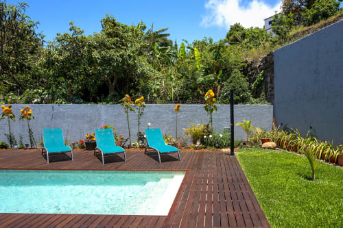Piscina turquesa com espreguiçadeiras e jardim luxuriante na villa Paradise House em Calheta, Portugal