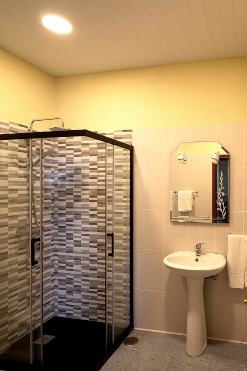 Banheiro moderno da villa Paradise House Calheta com chuveiro walk-in, pia pedestal e espelho iluminado