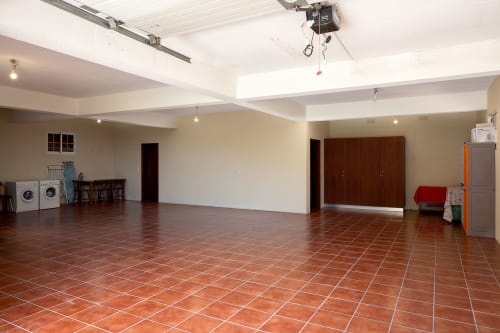 Ampla área comum da villa Paradise House Calheta com ladrilhos de terracota, vigas de teto brancas e portas de madeira