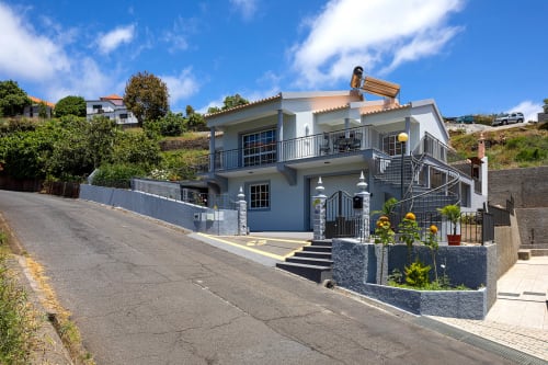 Vila Paradise House em Calheta, Portugal, com exterior azul-acinzentado, terraço multinível, arquitetura moderna e jardins bem cuidados