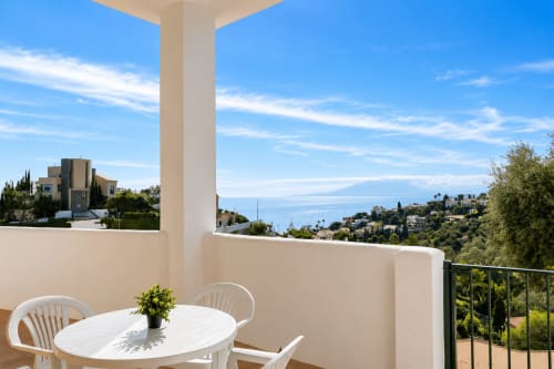 Terrace with white dining table overlooking Málaga coast and mountains, Apartamentos Axarent