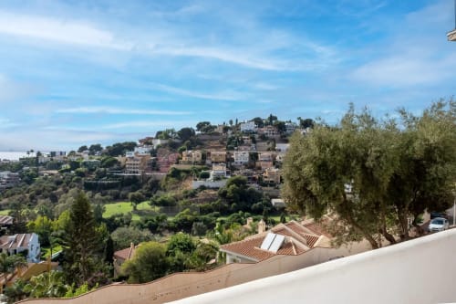 Hilltop Málaga apartment complex with Mediterranean gardens, terracotta roofing, and city views overlooking lush green