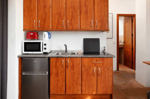 Compact kitchenette with wooden cabinets, microwave, stove, sink and laptop at Apartamentos Turísticos Axarent in Málaga