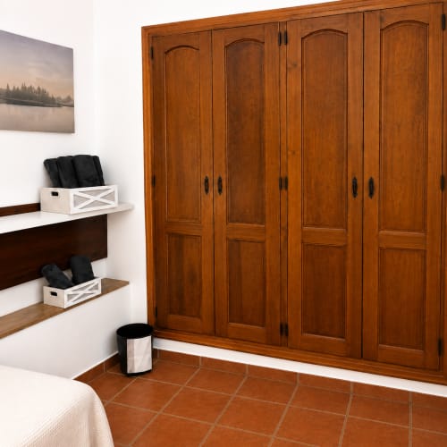 Wooden wardrobe armarios in Málaga apartment bedroom with shelving and coastal décor