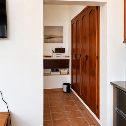 Hallway in Málaga apartment with wooden wardrobe, built-in shelving, terracotta floor, and white walls