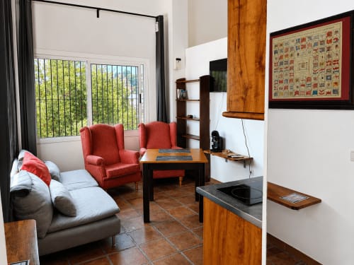 Bright living room with red armchairs, gray sofa, wooden accents, sea views, apartment in Málaga