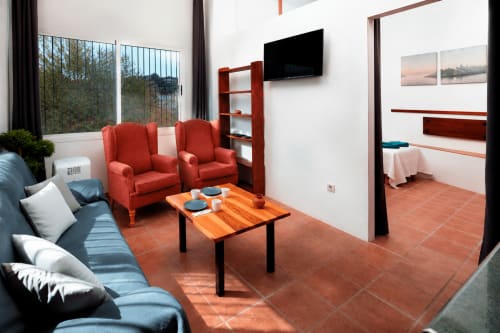 Modern living room at Apartamentos Turísticos Axarent in Málaga with red armchairs, sofa, wooden table, and sea views