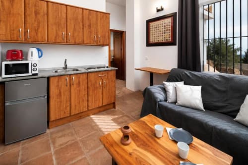 Modern apartment living area in Málaga with wooden kitchen, black sofa, and sea view balcony at Axarent