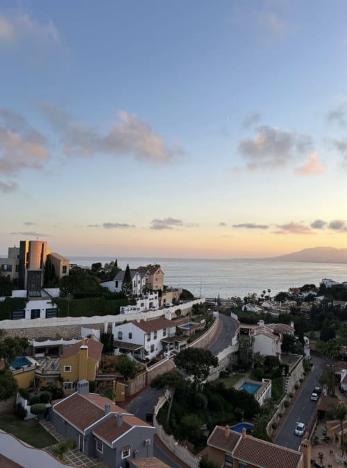 Sunset view of Axarent Apartments in Málaga with Mediterranean Sea, terraced whitewashed homes, and mountains across the bay