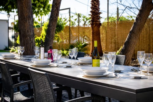 Outdoor dining table set with white plates, wine glasses, and bottles under shaded trees at Apartamentos Turísticos Axarent,