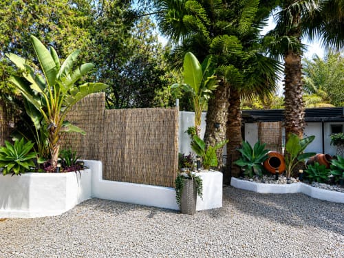 Modern courtyard with white planters, palm trees, wooden fence, and gravel pathway at Apartamentos Turísticos Axarent in
