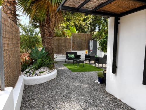 Modern patio at Apartamentos Turísticos Axarent with seating area, palm tree, white pergola, and manicured lawn in Almayate