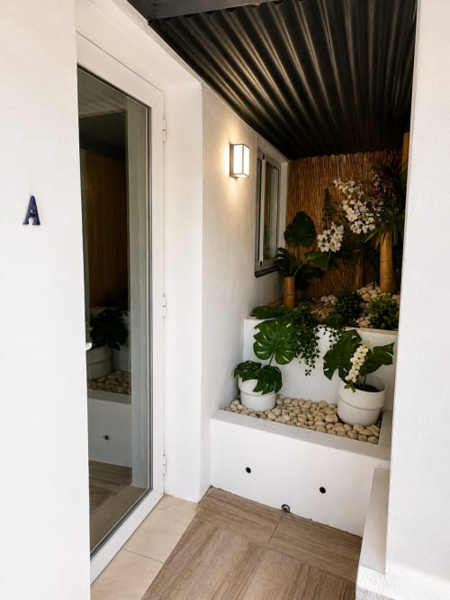 Modern apartment entrance with white walls, potted plants, and decorative flowers in Almayate Alto