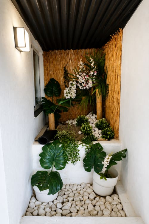 Cozy garden patio at Apartamentos Turísticos Axarent with potted plants, white stones, and bamboo screening in Almayate Alto