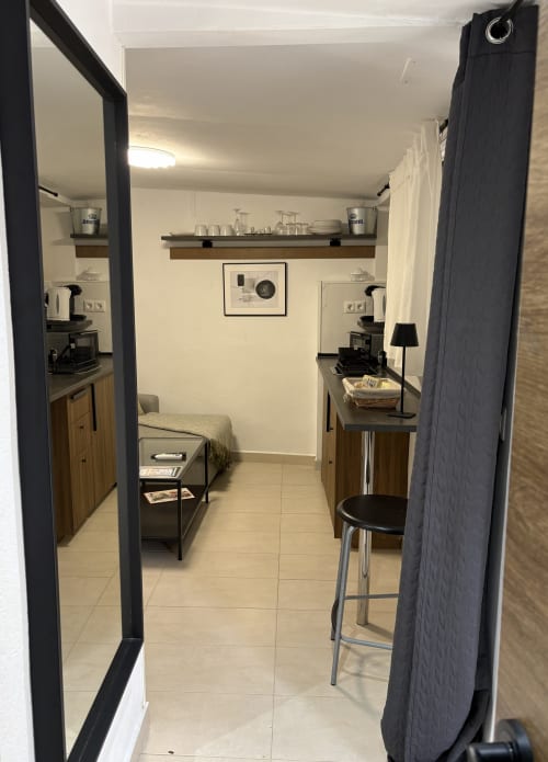 Modern apartment kitchenette with wooden cabinets, bar seating, and bedroom view at Axarent Almayate Alto
