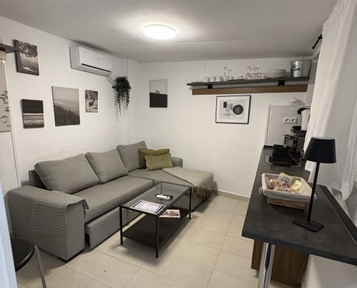 Modern living room in Almayate apartment with gray sofa, coffee table, kitchenette, and wall art