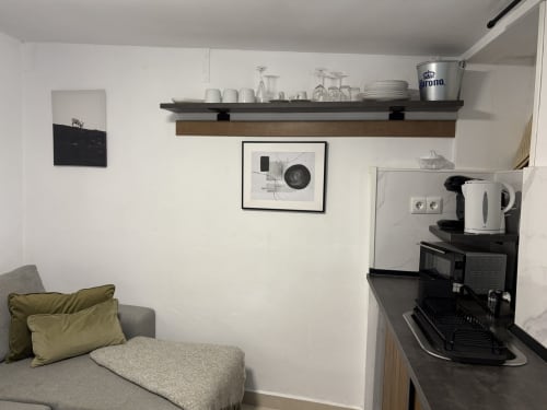 Studio apartment kitchenette with sofa, shelving, coffee maker, and minimalist wall art at Axarent in Almayate Alto