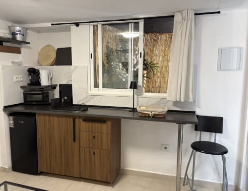 Modern kitchenette with wooden cabinets, black countertop, and bar seating overlooking sea view balcony at Almayate apartment