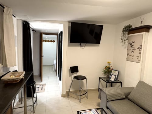 Modern studio apartment living area with sofa, kitchenette, TV, and decorative elements in Almayate Alto beach property