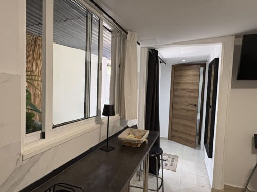 Modern apartment hallway with black desk, window with sea view, wooden door, and white tiled flooring at Apartamentos