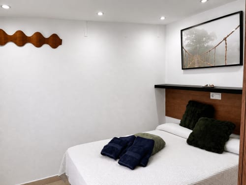Modern bedroom in Almayate Alto apartment with white bedding, black cushions, wooden headboard, and framed bridge artwork