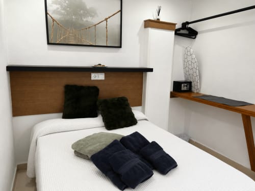 Cozy bedroom at Apartamentos Turísticos Axarent in Almayate Alto with white bed, black cushions, wooden headboard, and modern