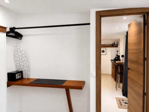 Modern apartment workspace with wooden desk, black rail, and open doorway to kitchen at Apartamentos Turísticos Axarent,