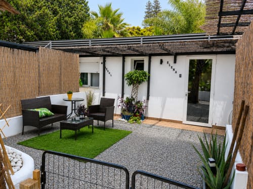 Modern patio at Apartamento 2 Playa Almayate with lounge seating, artificial grass, and white walls surrounded by wooden