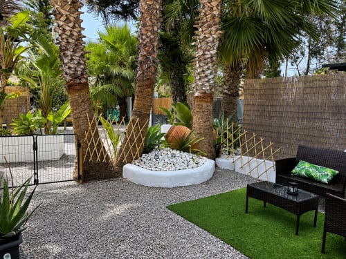 Contemporary patio with palm trees, white seating area, gravel ground, artificial grass, and black furniture at Apartamentos
