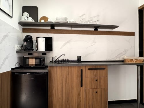 Modern kitchen area with wooden cabinets, black countertop, marble backsplash, and open shelving in Almayate Alto apartment