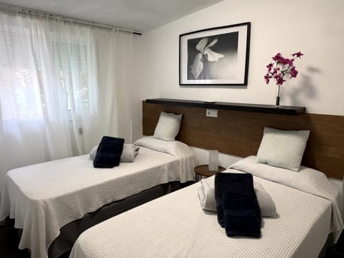 Twin beds with white linens in a modern apartment bedroom at Axarent hotel near Almayate beach, Spain
