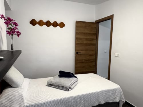 Modern bedroom at Apartamentos Turísticos Axarent in Almayate Alto with white bedding, wood door, purple flowers, and