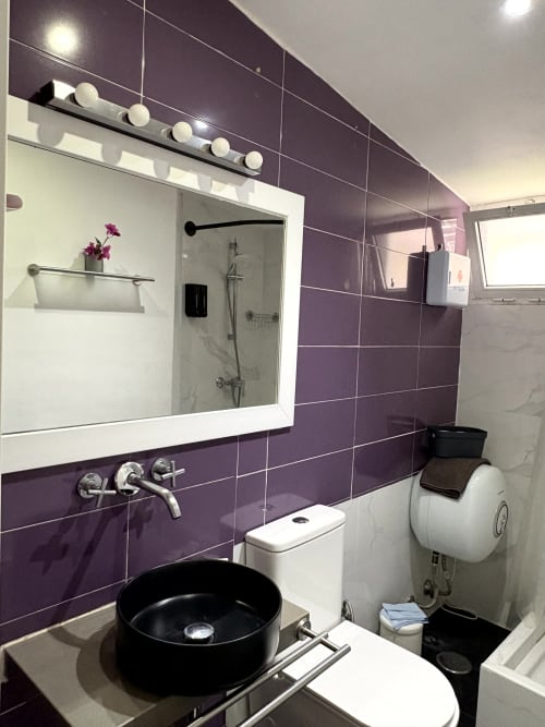 Modern bathroom at Apartamentos Turísticos Axarent with purple tiles, black sink, mirror with lighting, and shower enclosure