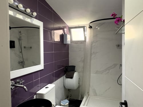 Modern bathroom in Almayate Alto apartment with purple tile accent wall, white marble finishes, and dual showers with vanity