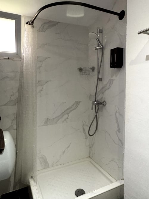 Modern shower enclosure with marble-look walls and rainfall showerhead at Apartamentos Turísticos Axarent, Almayate Alto