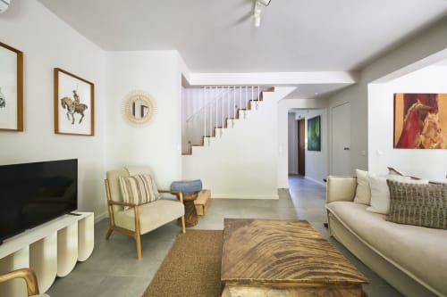 Moderno salón en villa d'Aura Aroeira con sofá crema, mesa de madera, chimenea y escalera hacia el nivel superior