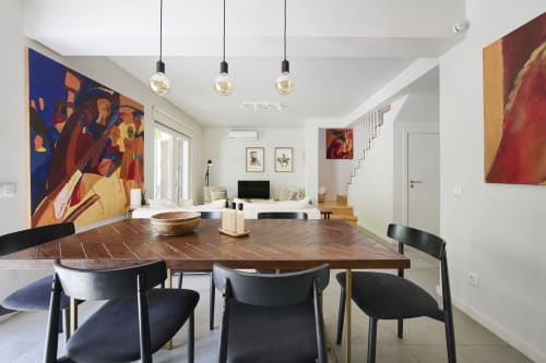 Comedor moderno de villa con mesa de madera, sillas negras, lámparas colgantes y arte colorido en el resort Aroeira