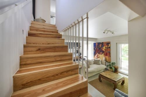 Escalera de madera moderna con barandillas blancas hacia la luminosa zona de estar de la villa en el resort Aroeira, Portugal