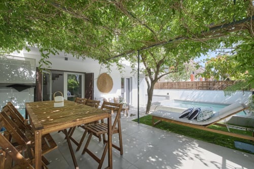 Terraza de villa con mesa de comedor de madera, vista a la piscina y dosel de árboles frondosos en República do Sul, Aroeira