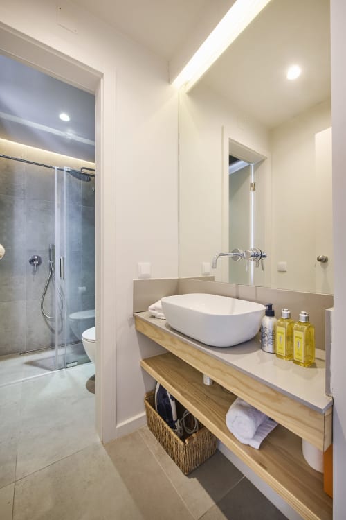 Baño moderno con lavamano ovalado blanco, mueble de madera y ducha con mampara de cristal en villa Republica do Sul, Aroeira