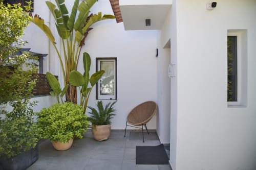 Entrada de villa moderna en República do Sul con plantas tropicales exuberantes, silla tejida y diseño minimalista en Aroeira, Portugal