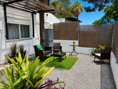 Private patio at Apartamentos Turísticos Axarent in Almayate Alto with seating, tropical plants, and reed fencing