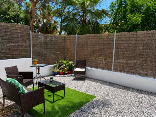 Private patio with wicker seating, artificial grass, and brick privacy fencing at Apartamentos Turísticos Axarent, Almayate