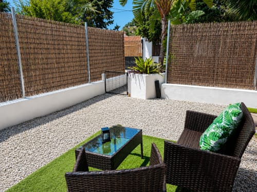 Patio seating area with rattan furniture, blue table, and green artificial grass at Apartamentos Axarent, Almayate Alto